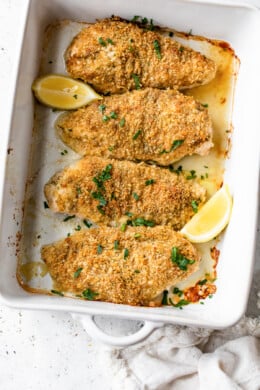 baked breaded chicken breast with lemons in a platter