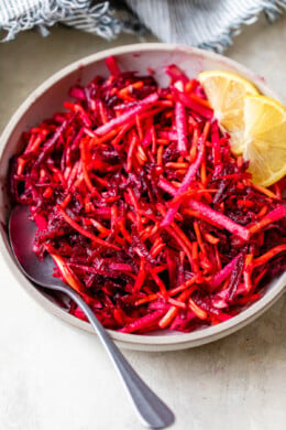 Raw Beet Salad with Apples and Carrots and lemon wedges.