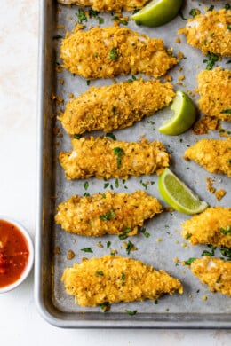 Tortilla Encrusted Chicken Tenders with lime wedges